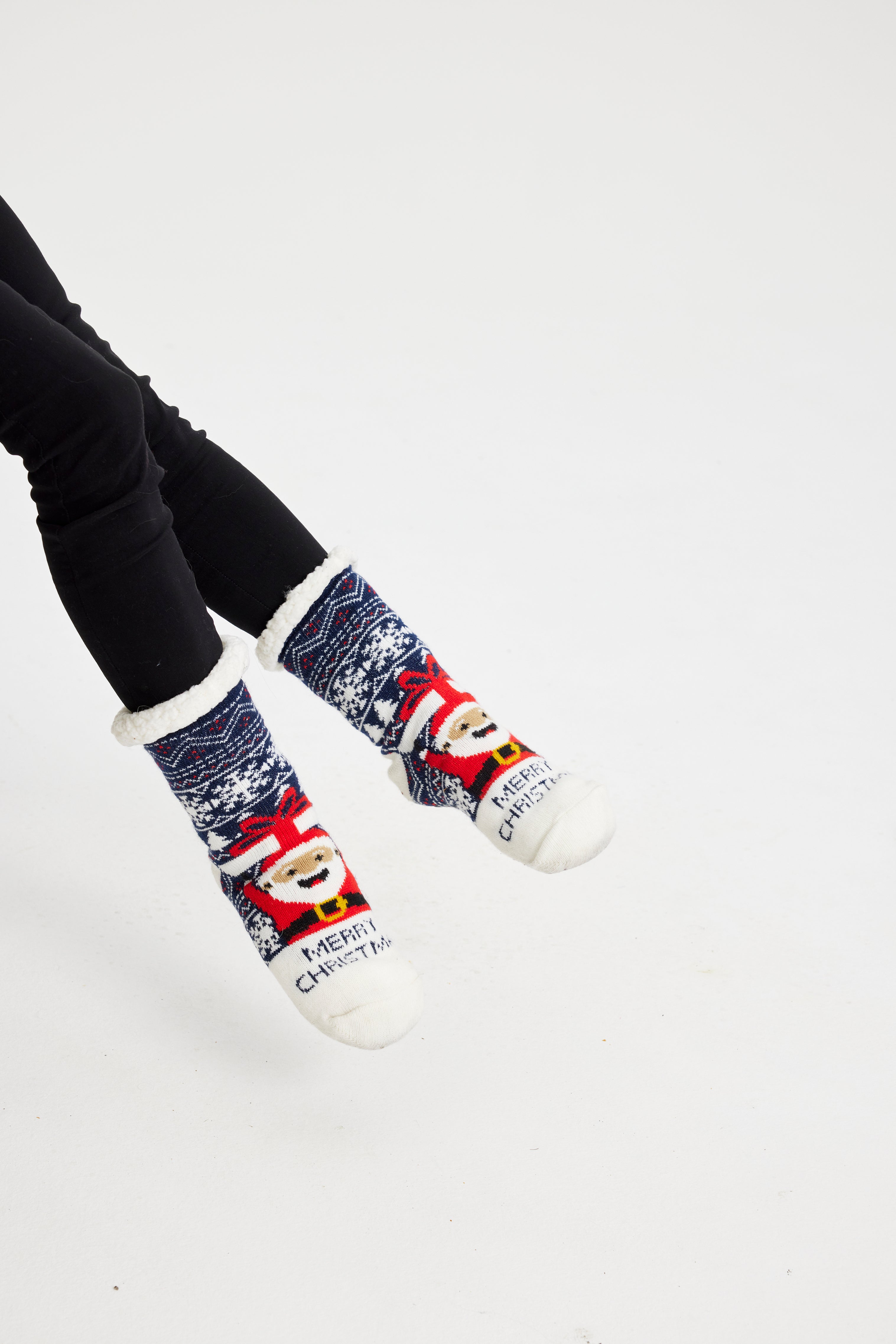 Un paio di piedi che indossano calzini di Natale bianchi, rossi e blu.